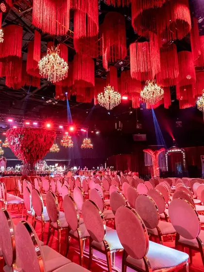 This wide shot shows the extensive seating arrangement, emphasizing the scale of the event and the visual impact of the uniform red chairs and plush sofas.