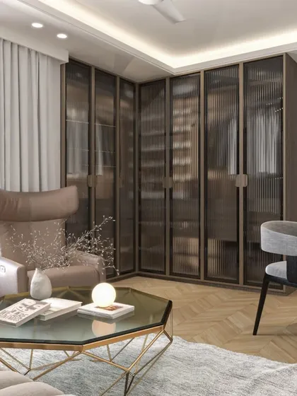 This room features a walk-in closet with fluted glass doors, offering a hint of the contents without full exposure. The design combines a cozy reading corner with practical storage, all tied together with a warm, neutral palette and herringbone flooring.