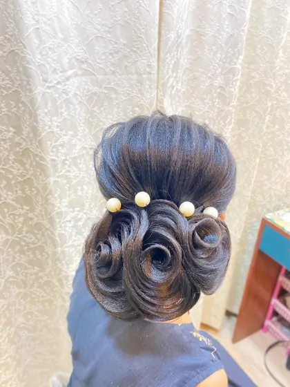 A clear, centered shot of the student's rose bun, showing the neatness of the swirls and the polished finish.