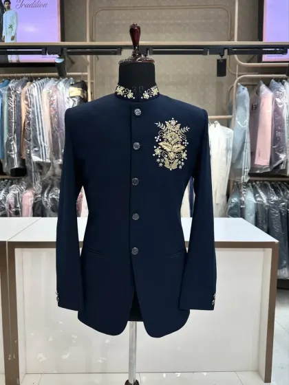 A classic navy blue Jodhpuri suit with a single, elegant gold embroidered motif on the chest and collar. This is a timeless design for any formal occasion.