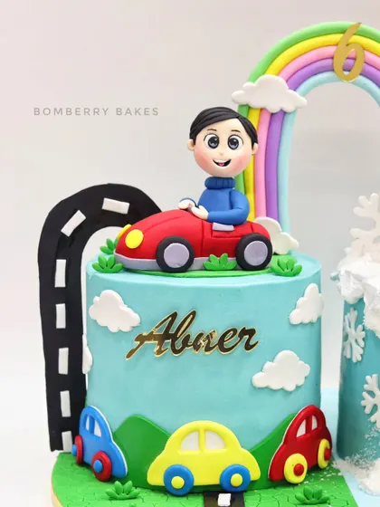 The other side of the twin's birthday cake, this one with a car theme. It features a personalized figurine of the birthday boy in his red car, driving on a fondant road under a rainbow.