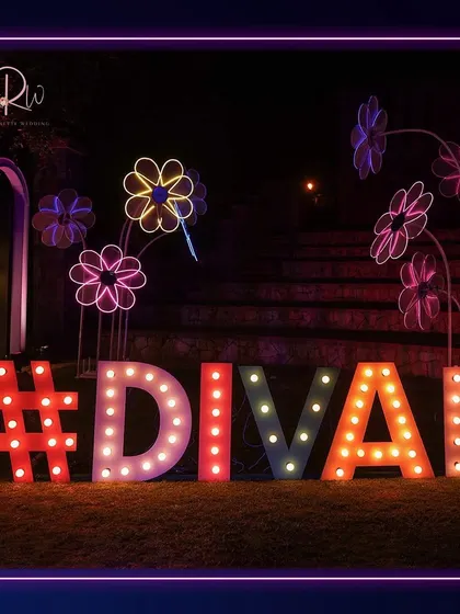 A fun and colorful photo op for a neon party, featuring a large marquee sign with the event's hashtag and whimsical neon flower sculptures.