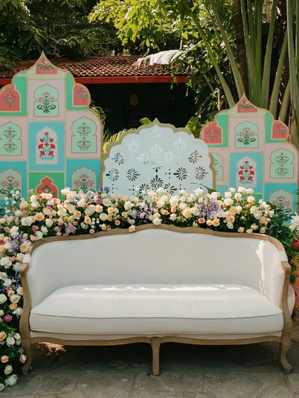 A perfect photo opportunity with a custom-designed backdrop for a Mehendi ceremony. The pastel-colored panels with traditional motifs and lush floral arrangements create a beautiful and memorable setting.