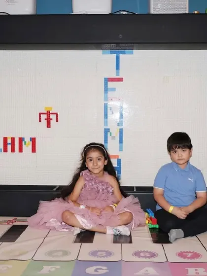 Two children sit in front of our giant Lego wall, a perfect spot for creative building and play.