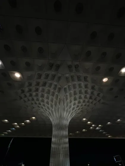 A direct upward shot of one of the supporting pillars at Mumbai Airport's T2, showing the intricate geometric pattern of the ceiling.