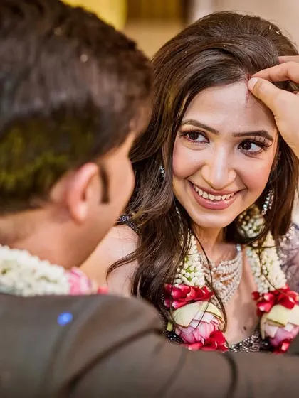 A close-up of a sacred wedding moment. The groom applies the tika to the bride's forehead, and her happy, trusting gaze says it all.