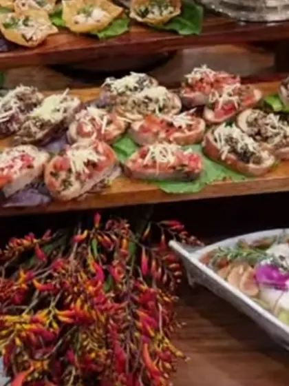 Open-faced little bites line the wooden boards in our Bengaluru home grazing setup, with flowers and other dishes visible behind them.