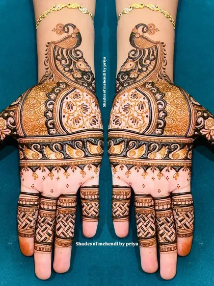 An example of intricate Indian mehendi with beautiful symmetry. This design features majestic peacocks and detailed patterns covering both hands, perfect for a bride who loves classic and elaborate henna art.