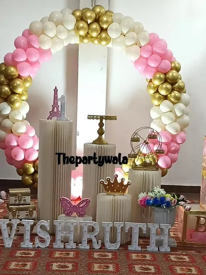 A pink, white, and gold balloon ring with 'BABY' blocks, suitable for a first birthday or baby shower.