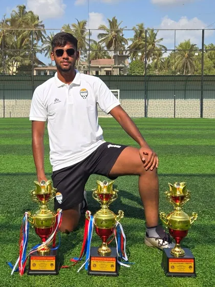 A coach with the trophies won by our academy teams. We are proud of the winning culture we have built.