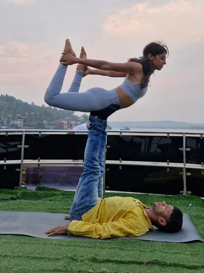 A beautiful bow pose, or Dhanurasana, in the air during an Acro Yoga session on a yacht. This requires so much trust between the base and the flyer.