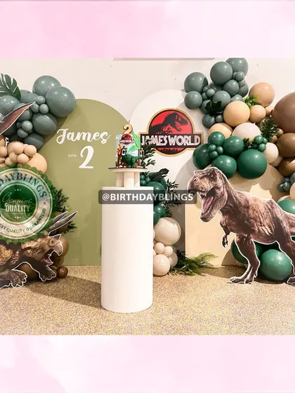 The full Jurassic World setup, with multiple dinosaur cutouts and a themed cake plinth.