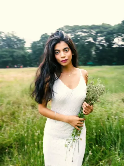 A beautiful, direct-to-camera portrait holding wildflowers. The motion in the background gives a sense of a breezy, open field.