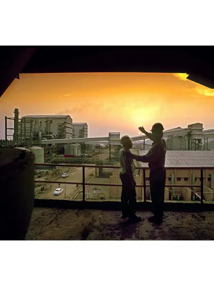 Two figures silhouetted against a sunset view of a factory. This image tells a story of vision and progress, making it ideal for a corporate annual report.