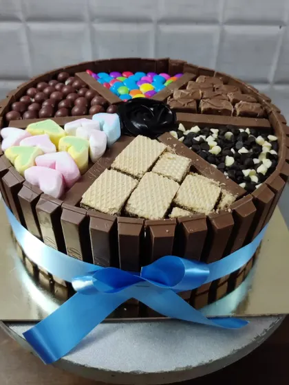 The ultimate chocolate lover's dream, my KitKat overload cake. This creation is packed with different treats in each section, including marshmallows, wafers, chocolate chips, and gems.