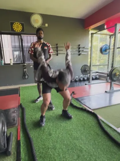 A coach guides a client through a battle rope slam, ensuring explosive power is generated correctly from the hips.