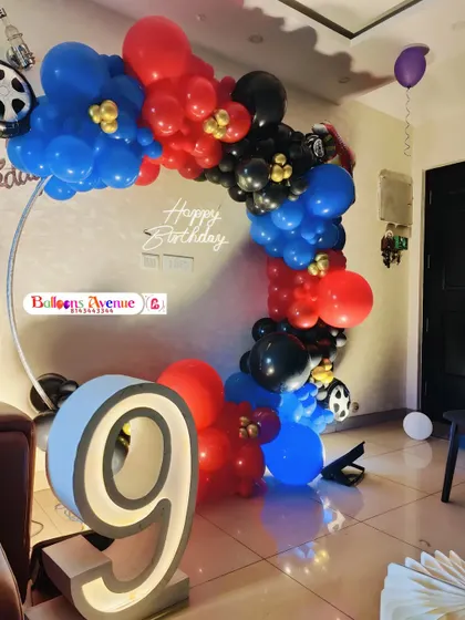 A high-energy car-themed birthday party with a balloon arch in red, blue, and black, complete with wheel foil balloons.