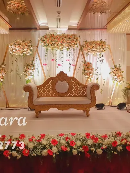 A beautiful reception stage featuring hanging floral arrangements on geometric wooden frames. The soft lighting and rustic elements create a warm and inviting atmosphere.
