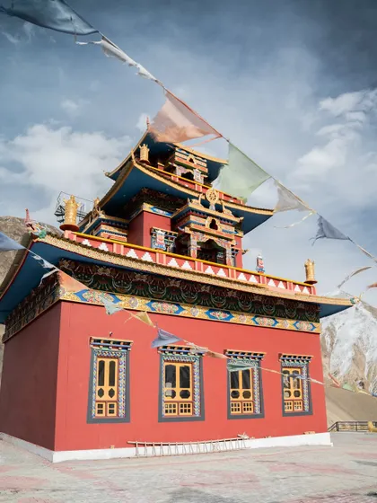 Images of the colorful Gue Monastery against the backdrop of snow-dusted mountains. The photos capture the intricate details of the stupa and the traditional Tibetan architecture.