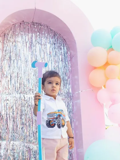 A little guest holds a prop microphone, ready for his moment in the spotlight. The pastel balloon decor and shimmering backdrop create a fun and festive atmosphere for all the kids.