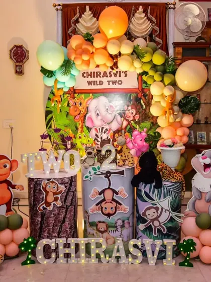 A fun-filled jungle party for Chirasvi's "Wild Two" birthday. This setup is packed with character, featuring cutouts of a monkey, rabbit, and tiger alongside themed pedestals.