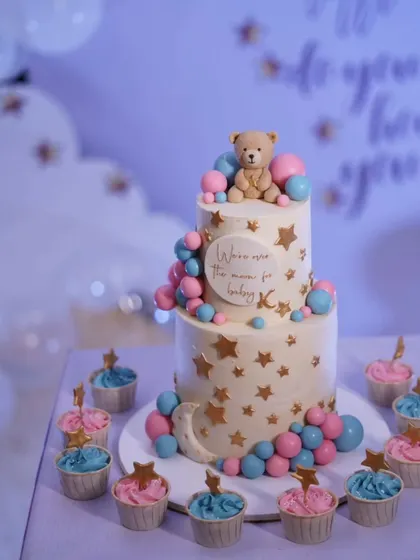 Another angle of the "Over the Moon" baby shower cake, showing the delicate details and the accompanying themed cupcakes.