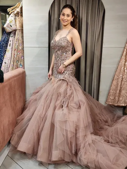 Which gown suited her better? This client is trying on a beautiful dusty pink fish-tail gown with a long, ruffled trail.