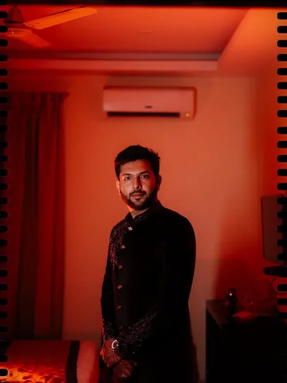 A portrait of the groom in a room with dramatic red lighting.