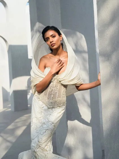 Another view of the ivory hooded gown, where delicate embroidery catches the light, tracing gentle patterns across its surface. It is a piece that exists in the space between movement and stillness.