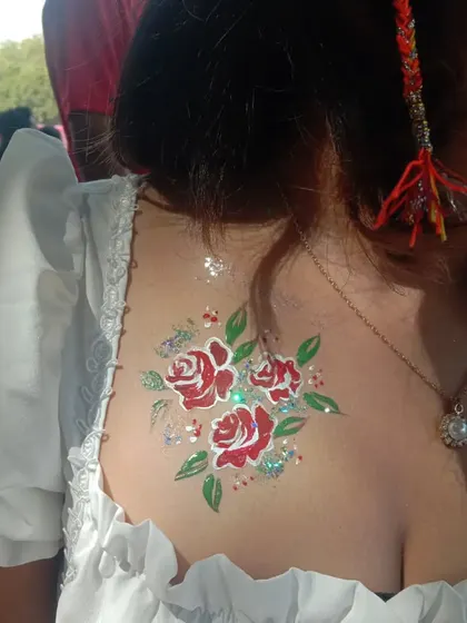 A lovely bouquet of red roses with green leaves and a sprinkle of glitter, painted on the upper back. This is a great placement for off-the-shoulder tops.