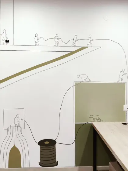 Another section of the office mural, showing line-art figures connected by a single thread, symbolizing teamwork and connectivity.