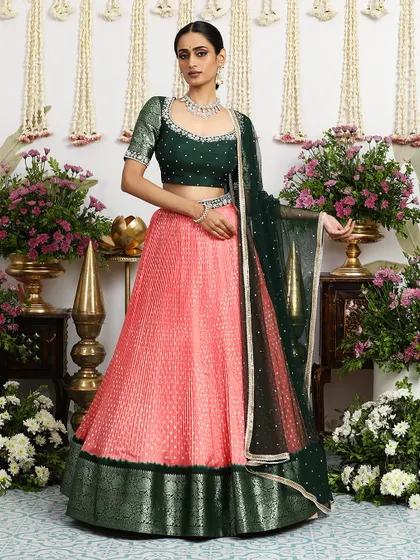 Another elegant pose in the coral and green lehenga, highlighting its graceful silhouette.