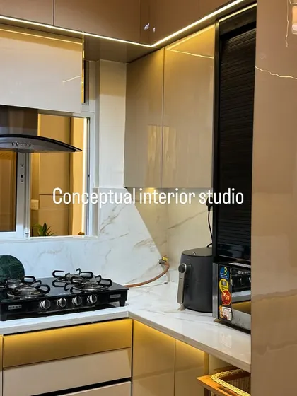 A beautiful picture of a 3BHK interior, showing the kitchen with high-gloss cabinets, a marble-finish backsplash, and a rolling shutter for appliances.