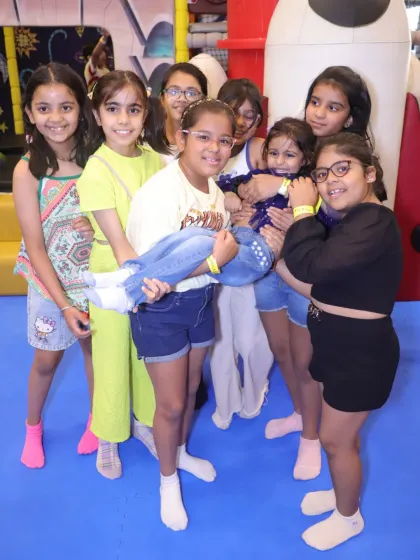 Friends of all ages having fun together. Here, older girls lift up one of the younger guests in a sweet moment of friendship.