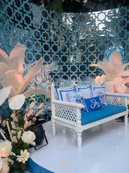A graceful seating area for the couple, with a white bench, custom-printed blue cushions, and a beautiful lattice backdrop.