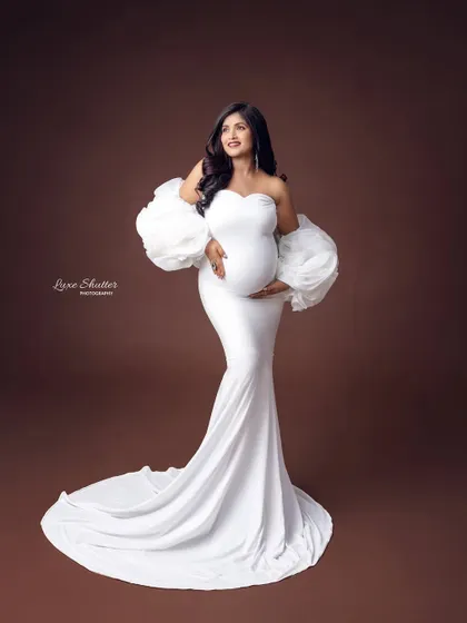 This white bodycon gown with dramatic puff sleeves is a client favorite. It creates a stunning silhouette against a warm, earthy brown backdrop for a modern yet timeless feel.