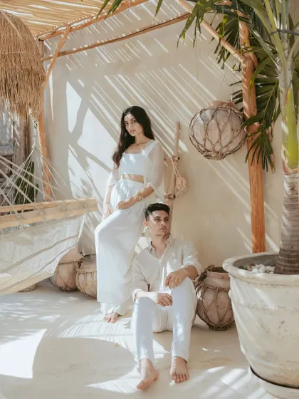 This portrait uses the interesting patterns of light filtering through a bamboo roof to create a visually striking effect. The couple's pose is strong and confident, blending editorial style with the tropical aesthetic of their Bali location.