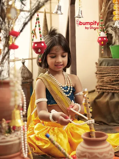 A candid moment of our little Radha playing with props during her Janmashtami photoshoot, her curiosity and innocence shining through.