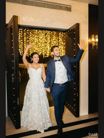 The grand entrance to the reception. The couple waves to their guests as they walk through a beautifully lit doorway, ready to celebrate.