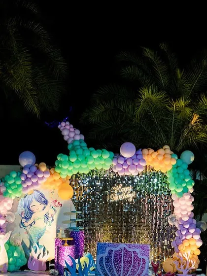 Another view of the outdoor Mermaid theme party. This angle shows the custom-printed mermaid backdrop that was placed in front of the sequin wall, adding another layer to the underwater theme.