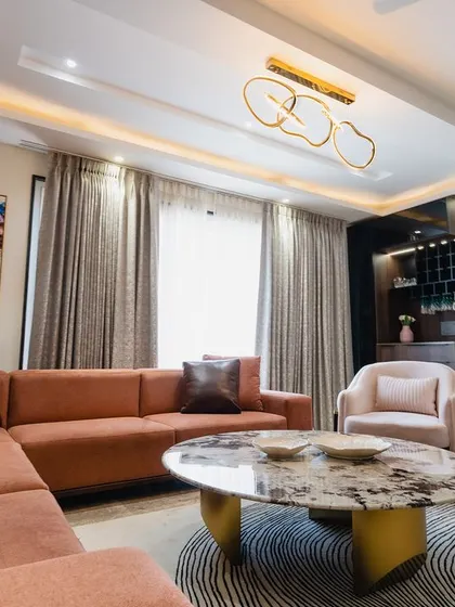 A vibrant painting adds a pop of color to this living room, which features a mix of peach and off-white seating. The modern chandelier adds a sculptural element to the ceiling.