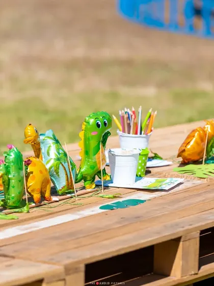 The kids' activity table, decorated with dinosaur-shaped foil balloons and coloring supplies.