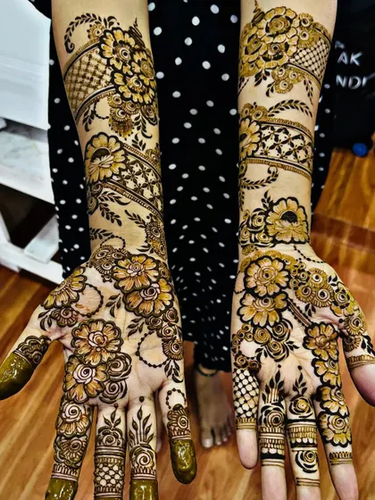 A stunning full-coverage floral design. This Arabic-style mehndi features bold flowers and vines that wrap around the hands and arms, creating a very dynamic and beautiful look.