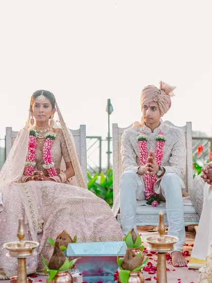 A wide shot of the wedding ceremony, with the couple and their families seated around the holy fire against a serene backdrop. This captures the solemnity and togetherness of the moment.