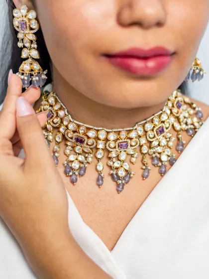 A close-up of a beautiful kundan choker with purple stone accents and pearl droppings. This piece adds a unique touch of color to a traditional design.
