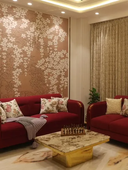 A bold red sofa set against a floral wallpapered accent wall adds a touch of vibrant elegance to this living area in the Harmony Home project.