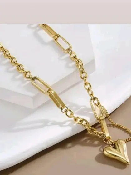 A close-up of the stylish paperclip and chain link bracelet with a puffy heart charm. A modern design with a romantic touch.
