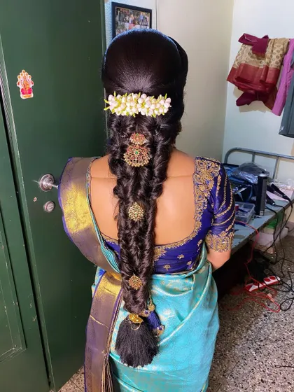 This is an intricate, multi-layered braid for a bride, decorated with jasmine and gold jada pieces. It’s a statement look for a wedding ceremony.