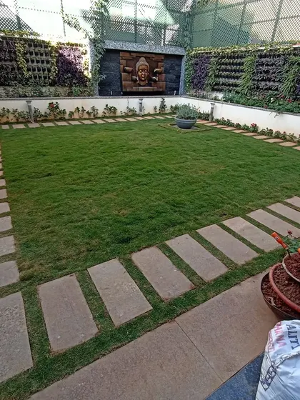 This image showcases how living vertical gardens can be integrated into a larger landscape design. Here, they serve as a beautiful, living backdrop for a manicured lawn and stone patio.