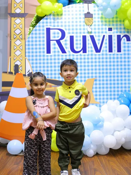 Two friends pose in front of the "Under Construction" backdrop. The bright colors and fun graphics make for a great photo spot.